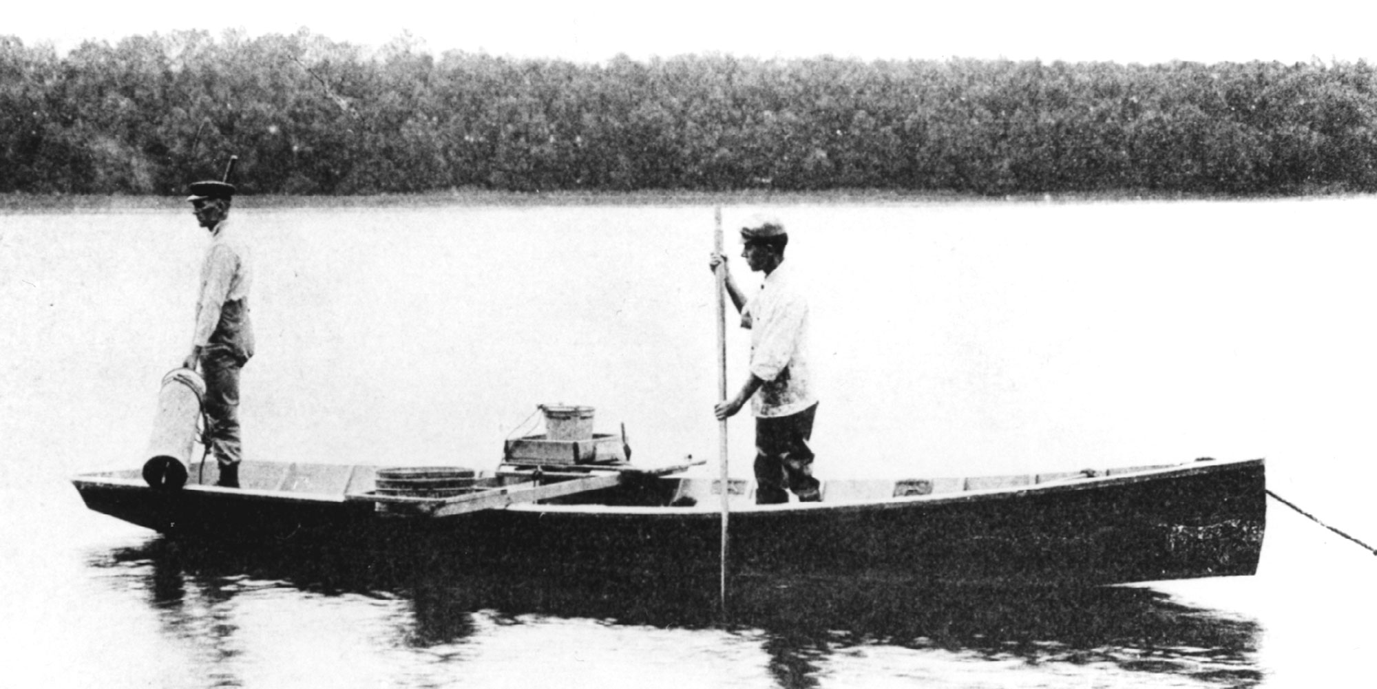 Two men standing in a canoe on Quiver Lake, circa 1935.